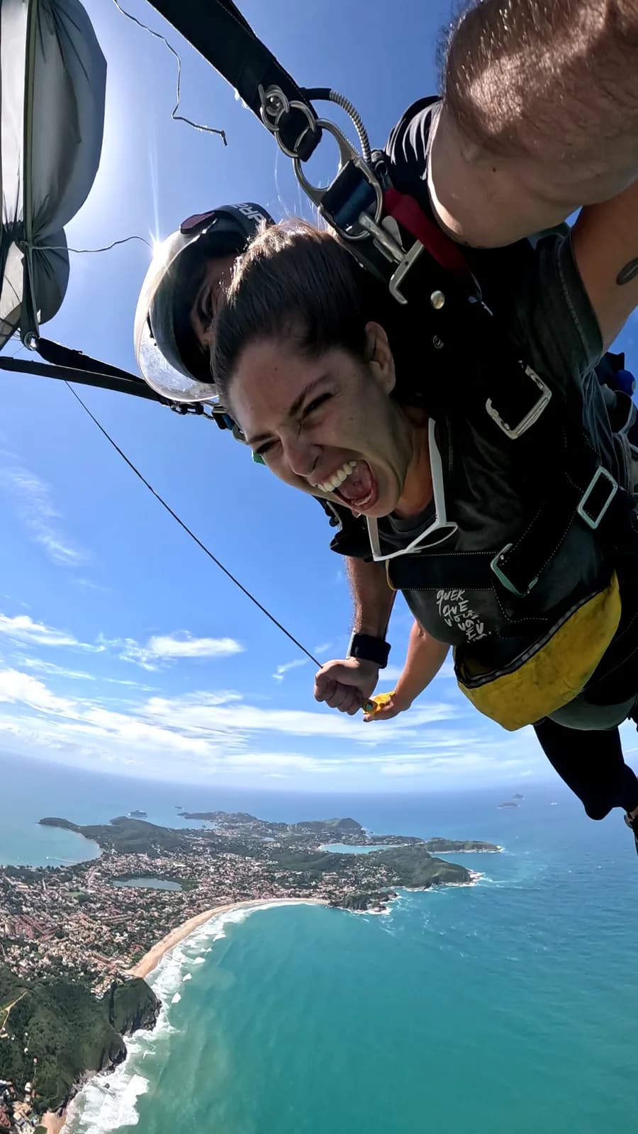 Saltador sorrindo durante a queda livre em salto duplo sobre Búzios